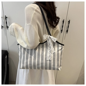 Black and white striped canvas tote bag detail featuring a delicate white lace bow accent