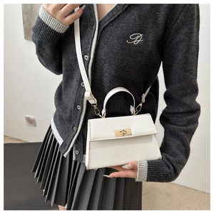 Close-up of a white lychee grain leather handbag featuring a golden rectangular twist lock