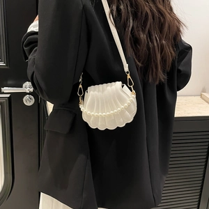 Sac coquillage blanc avec anse en perles porté par un mannequin en veste blazer noire