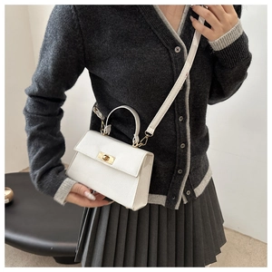 Close-up of white lychee pattern crossbody bag with a golden metal twist lock closure