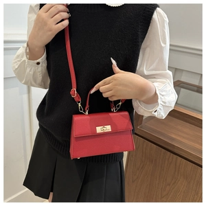Detail of red lychee grain leather crossbody bag with gold tone metal twist lock closure