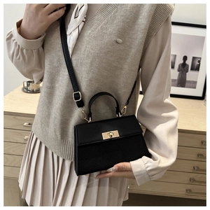 Detail of black lychee texture handbag with golden swivel lock and adjustable strap