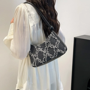 Black denim crescent bag with white frayed diamond pattern and leather shoulder strap