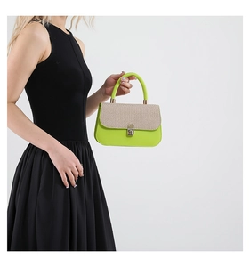 Detail of neon green and beige woven underarm bag with metallic buckle held by model