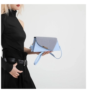 Détail du sac bandoulière bleu clair avec rabat tissé gris et boucle en métal doré