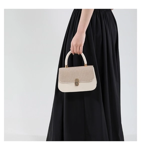 Detail of cream vintage underarm bag featuring woven texture flap and gold metal clasp