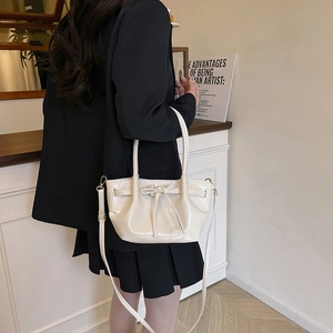 Chic cream bow shoulder bag with glossy pleated leather and elegant gold hardware