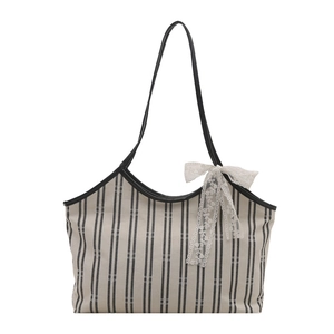 Striped canvas tote bag with black leather straps and white lace bow detail