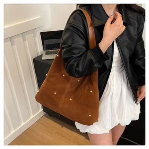 Detailed macro view of dark brown suede bag with gold round stud accents and leather strap
