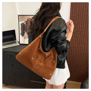 Detail of brown suede hobo bag featuring golden circular studs and minimalist shoulder strap