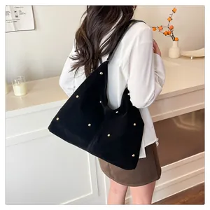 Detail of black suede tote bag with gold round metal rivets and vertical stitching