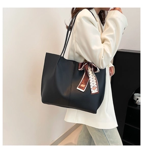 Minimalist black leather tote bag featuring a decorative geometric print silk scarf detail