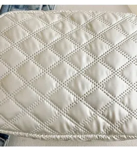 Détail du sac beige en tissu oxford matelassé avec surpiqûres en losanges sur denim