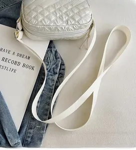 Détail du sac bandoulière argenté matelassé avec sangle tissée blanche et motif losanges