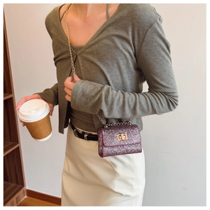 Detail of a purple sequined mini crossbody bag with gold chain strap and metal clasp