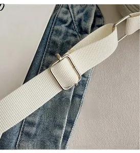 Détail de la bandoulière en toile blanche réglable avec boucle en métal argenté