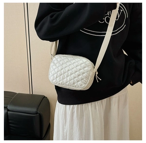 Détail du sac bandoulière blanc matelassé avec large sangle en tissu sur modèle