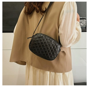 Détail d'un sac bandoulière matelassé noir montrant les coutures et la fermeture