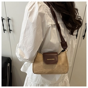 Detail of vintage beige canvas shoulder bag with brown leather flap and gold lettering