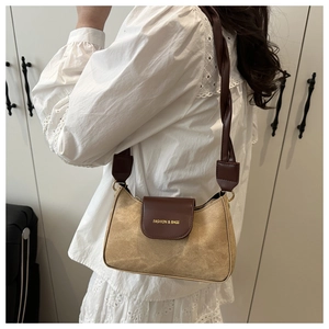 Detailed side view of khaki suede underarm bag with brown braided strap and gold lettering