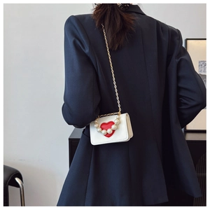 Mini sac blanc chic avec cœur rouge et perles porté en bandoulière sur un mannequin