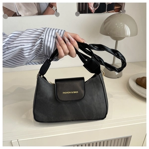 Close-up of black textured fabric handbag featuring leather trim and woven handle detail