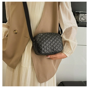 Détail d'un sac à bandoulière matelassé noir avec sangle large porté par un mannequin