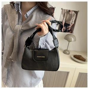 Detail of black leather crescent bag with golden Fashion & Bags print and woven handle