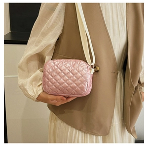 Détail du sac bandoulière rose matelassé avec sangle large et texture nylon en losange