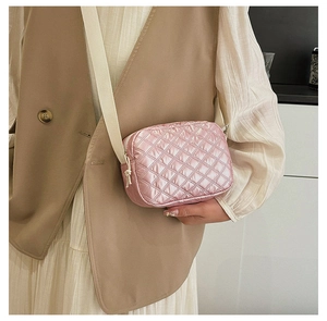 Détail du sac bandoulière rose matelassé avec texture douce et large sangle réglable