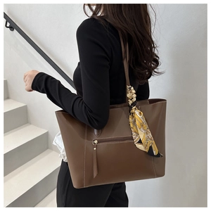 Brown tote bag detail with decorative floral silk scarf and fine contrast stitching