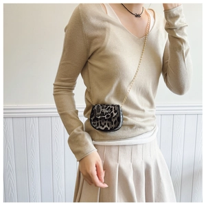 Close-up of mini leopard print saddle bag with elegant gold chain strap on a model