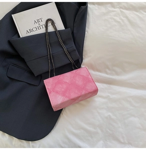Detail of pink quilted crossbody bag with silver chain strap on a grey suit jacket