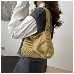 Close-up of mustard green corduroy tote bag showing vertical ribbed texture and shoulder strap