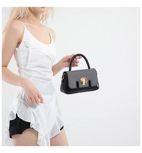 Détail du sac à main en tissu gris avec serrure ronde dorée et poignée en cuir noir