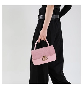 Detailed shot of pink textured handbag with elegant gold oval metal clasp and handle
