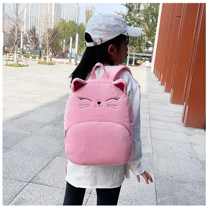 Rear view of a child wearing a cute pink plush cat backpack with 3D ears on a street