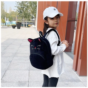 Close-up of plush black cat backpack for kids featuring embroidered facial details
