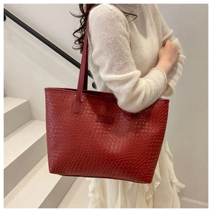 Detail of red leather woven tote bag on shoulder with sleek logo leather patch