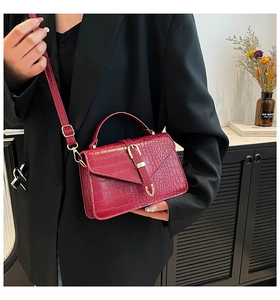 Fashionable red croc-patterned leather crossbody bag with a sleek gold buckle and strap