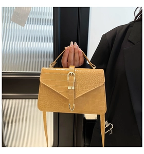 Detail view of yellow ginger crossbody bag with crocodile pattern and gold buckle
