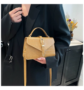 Model wearing a khaki faux crocodile handbag with a black blazer in a minimalist interior