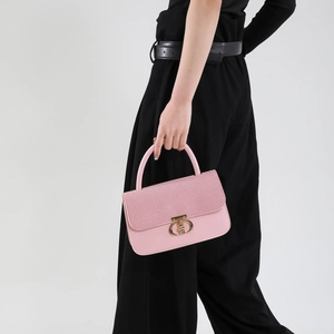 Pink patchwork small square bag with round gold lock shown by model in minimalist style