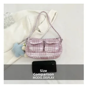Pink corduroy underarm bag size comparison with a phone on white fabric background