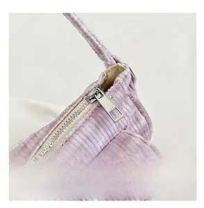 Close-up of smooth metal zipper on light purple corduroy handbag with striped texture