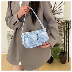 Primo piano di una borsa sottobraccio a quadri blu e bianchi con tasche su una modella