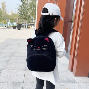 Kids black plush cat backpack with cute 3D ears and embroidery shown on a young model