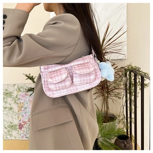 Dettaglio borsa a spalla in velluto rosa con stella, indossata su un blazer beige