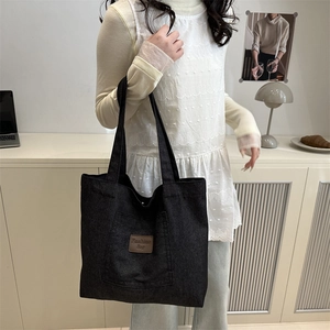 Black canvas tote bag with fashion leather tag and wide straps for daily commute