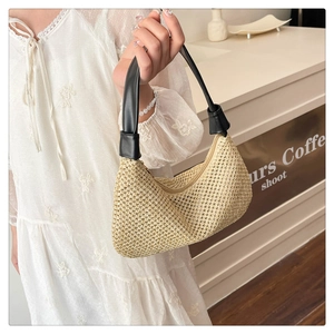 Detail der beige Stroh-Schultertasche mit schwarzem Ledergriff und gewebter Textur